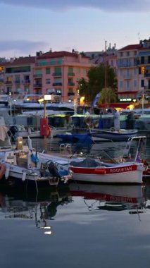 Cannes, Fransa - 26 Ağustos 2024: Gemiler arka planda binalarla birlikte akşamleyin Port de Cannes limanına yanaştı. Dikey