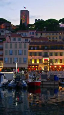 Cannes, Fransa - 26 Ağustos 2024: Gemiler arka planda binalarla birlikte akşamleyin Port de Cannes limanına yanaştı. Dikey