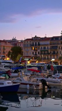 Cannes, Fransa - 26 Ağustos 2024: Gemiler arka planda binalarla birlikte akşamleyin Port de Cannes limanına yanaştı. Dikey