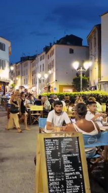 Antibes, Fransa - 29 Ağustos 2024: İnsanlar akşamları şehrin sokaklarında teraslarda oturuyorlar. Dikey