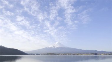 Kawaguchiko Gölü 'nün üzerindeki Fuji Dağı' nın muhteşem manzarası, parlak mavi gökyüzü ve tüylü beyaz bulutlar gün boyunca çarpıcı bir zemin oluşturuyor..