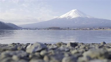 Görkemli manzara, karla kaplı Fuji dağının bir gölün sakin sularına yansıyarak Japonya 'nın manzaralı güzelliğini gözler önüne seriyor. Ön plandaki kayalara kaymaya odaklan.