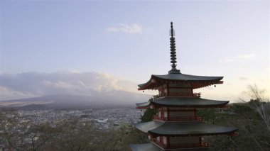 Chureito Pagoda, Fujikawaguchiko şehrine tepeden bakan ve güneş görkemli Fuji dağının arkasında batarken dimdik ayakta duruyor. Renkli mimari, akşam gökyüzü ile güzel bir tezat oluşturuyor..