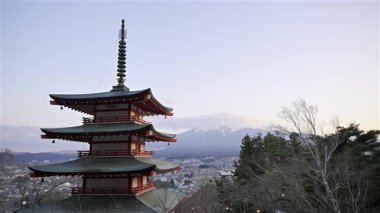 Chureito Pagoda, Fujikawaguchiko şehrine tepeden bakan ve güneş görkemli Fuji dağının arkasında batarken dimdik ayakta duruyor. Renkli mimari, akşam gökyüzü ile güzel bir tezat oluşturuyor..