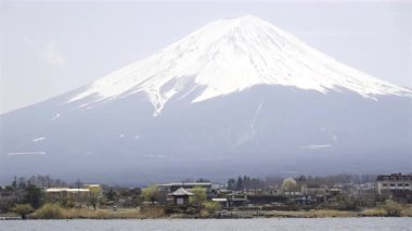 Fuji Dağı, Japonya 'daki göl kenarlarındaki karlı zirvelerle görkemli bir şekilde ayakta duruyor. Berrak bahar gökyüzü bu dingin manzaraya çarpıcı bir zemin sağlar..