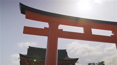 Fushimi Inari geleneksel türbesinin parlak kırmızı kapıları güneşli berrak gökyüzüne karşı dimdik ayakta duruyor.