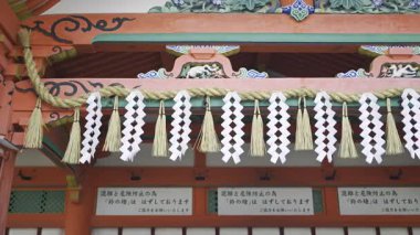 A vibrant shrine entrance featuring intricate wooden carvings and traditional decorations. Translation of text: ''Ring bell has been removed for safety''. Fushimi Inari, Kyoto, Japan