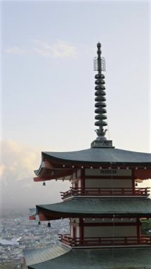 Chureito Pagoda, Fujikawaguchiko şehrine tepeden bakan ve güneş görkemli Fuji dağının arkasında batarken dimdik ayakta duruyor. Dikey video