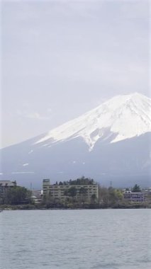 Sakin bir gölün üzerinde karla kaplı bir dağın bulunduğu nefes kesici bir manzara. Yakın binalar, açık bir günde doğal güzellikleri yansıtan canlı manzarayı yansıtıyor..