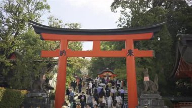 Kyoto, Japonya - 9 Nisan 2025: Renkli kırmızı kemer yolu, tarihi binalarla çevrili ünlü Fushimi Inari türbesini karşılıyor.