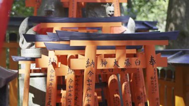 Kyoto, Japonya - 9 Nisan 2025: Her biri geleneksel karakterlerle işlenmiş küçük kırmızı torii kapıları. Sahne Japon kültürünün ve maneviyatının güzelliğini yakalıyor. Fushimi Inari