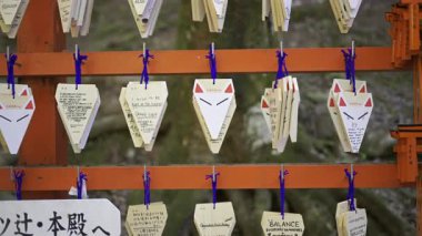 Kyoto, Japonya - 9 Nisan 2025: Ziyaretçiler tilki şeklinde ahşap plaketler asar, dileklerini ve dualarını yazarlar. Bu gelenek kültürel mirası yansıtır..