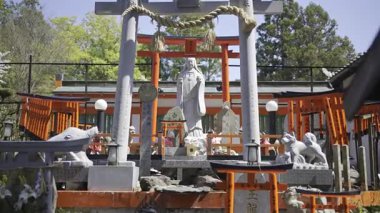 Kyoto, Japonya - 9 Nisan 2025: Ziyaretçiler Japonya 'da kırmızı torii kapıları ve karmaşık heykellerle süslenmiş huzurlu bir tapınağa hayran kaldılar.