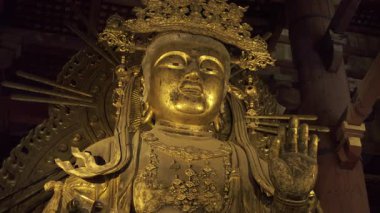 Nara, Japonya - 10 Nisan 2025: Todai-ji Budist tapınağındaki dingin altın Buda heykeli hafifçe aydınlatıldı. Büyük Buda Salonunun içi