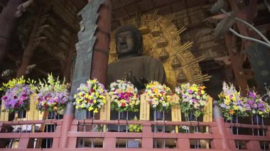 Nara, Japonya - 10 Nisan 2025: Tapınaktaki büyük Buda heykeli kuleleri, tabanında canlı çiçeklerle süslenmişti. Büyük Buda Salonunun içi
