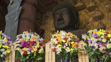 Nara, Japonya - 10 Nisan 2025: Todai-ji tapınağındaki büyük Buda heykeli. Renkli çiçek aranjmanları. Büyük Buda Salonunun içi