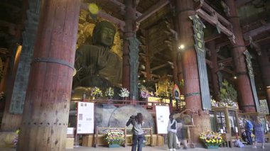 Nara, Japonya - 10 Nisan 2025: Todai-ji tapınağındaki Büyük Buda heykelinin zamanaşımı. Renkli çiçek aranjmanları. Büyük Buda Salonunun içi