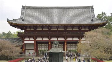 Nara, Japonya - 10 Nisan 2025: Japonya 'daki Todai-ji tarihi tapınağında toplanan kalabalık, serin bir açık hava ortamında baş döndürücü kiraz çiçekleri ve geleneksel mimarinin keyfini çıkarıyorlar..