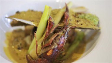 Bir midye kabuğu ve beyaz bir tabakta kremalı otla pişirilmiş kerevitin tamamını kapat.