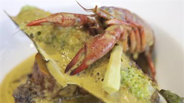 Bir midye kabuğu ve beyaz bir tabakta kremalı otla pişirilmiş kerevitin tamamını kapat.