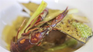 Bir midye kabuğu ve beyaz bir tabakta kremalı otla pişirilmiş kerevitin tamamını kapat.