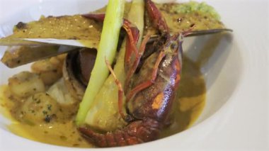 Bir midye kabuğu ve beyaz bir tabakta kremalı otla pişirilmiş kerevitin tamamını kapat.