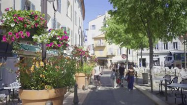 Antibes, Fransa - 3 Mayıs 2025: İnsanlar şehrin sokaklarında güpegündüz terasların yanında yürüyorlar