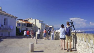 Antibes, Fransa - 4 Mayıs 2025: Nicolas Lavarenne heykeli yakınlarındaki Grand Defi kıyısında yürüyen insanlar