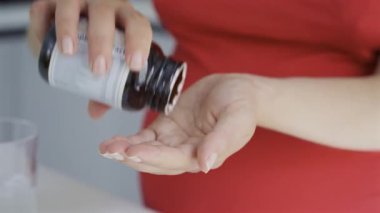 Hamile bir kadının avucunun içine balık yağı takviyesi dökerken.