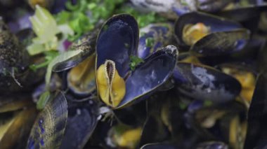 Üstünde yeşil soğan olan bir tencerede çoklu buharlı midyeleri kapat.