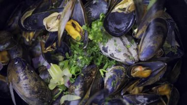 Üstünde yeşil soğan olan bir tencerede çoklu buharlı midyeleri kapat.