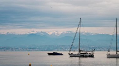 Antibes, Fransa - 6 Mayıs 2025: Arka planda dağlar ve şehirle birlikte denizde çok sayıda tekne