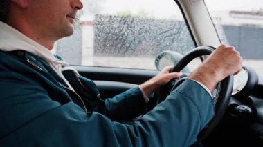 Yağmurda yolda araba süren bir adama yaklaş.