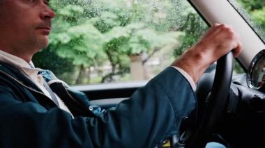 Yağmurda yolda araba süren bir adama yaklaş.