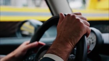 Bir adamın ellerini direksiyona koyup, yolda araba sürerken.