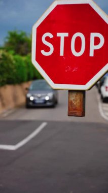Caddede hareket halindeki arabaların bulanık arka planına sahip bir dur işaretini kapat. Dikey