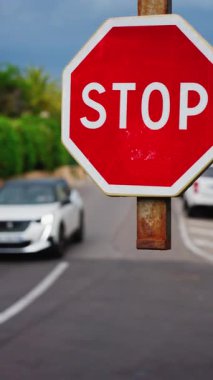 Caddede hareket halindeki arabaların bulanık arka planına sahip bir dur işaretini kapat. Dikey
