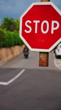 Caddede hareket halindeki arabaların bulanık arka planına sahip bir dur işaretini kapat. Dikey