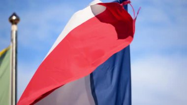 Arka planda mavi bir gökyüzü ile rüzgarda dalgalanan Fransa bayrağını kapatın.