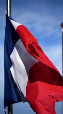 Arka planda mavi bir gökyüzü ile rüzgarda dalgalanan Fransa bayrağının yakınında. Dikey