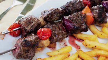 Restoranda ızgara domuz şiş, domates ve patates kızartması.