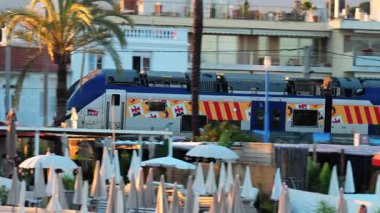 Cannes, Fransa - 13 Mayıs 2025: Akşamleyin sahilden geçen mavi tren