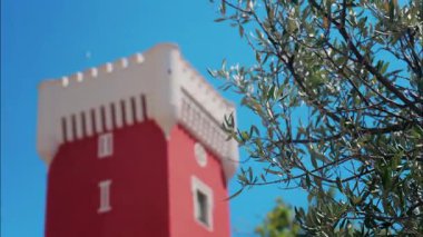 Kremat Şatosu 'nun kırmızı kulesinde mavi gökyüzünün üzerinde rüzgârda hareket eden yeşil ağaç.