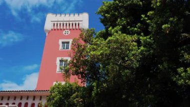 Kremat Şatosu 'nun kırmızı kulesinde mavi gökyüzünün üzerinde rüzgârda hareket eden yeşil ağaç.