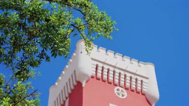 Kremat Şatosu 'nun kırmızı kulesinde mavi gökyüzünün üzerinde rüzgârda hareket eden yeşil ağaç.