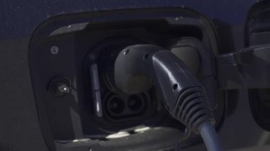 Siyah bir arabaya takılı elektrikli araba şarj aletini kapat.