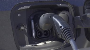 Siyah bir arabaya takılı elektrikli araba şarj aletini kapat.