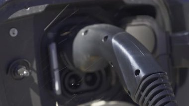 Siyah bir arabaya takılı elektrikli araba şarj aletini kapat.