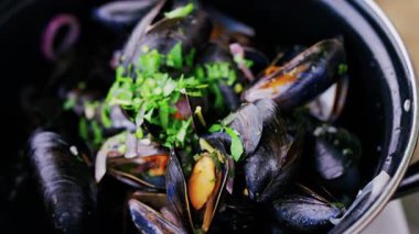 Çoklu buharlı midyeleri üzerinde maydanoz olan bir tencereye koy.