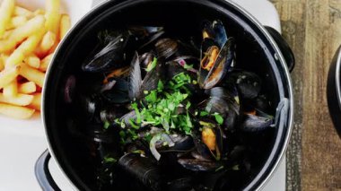 Çoklu buharlı midyeleri üzerinde maydanoz olan bir tencereye koy.